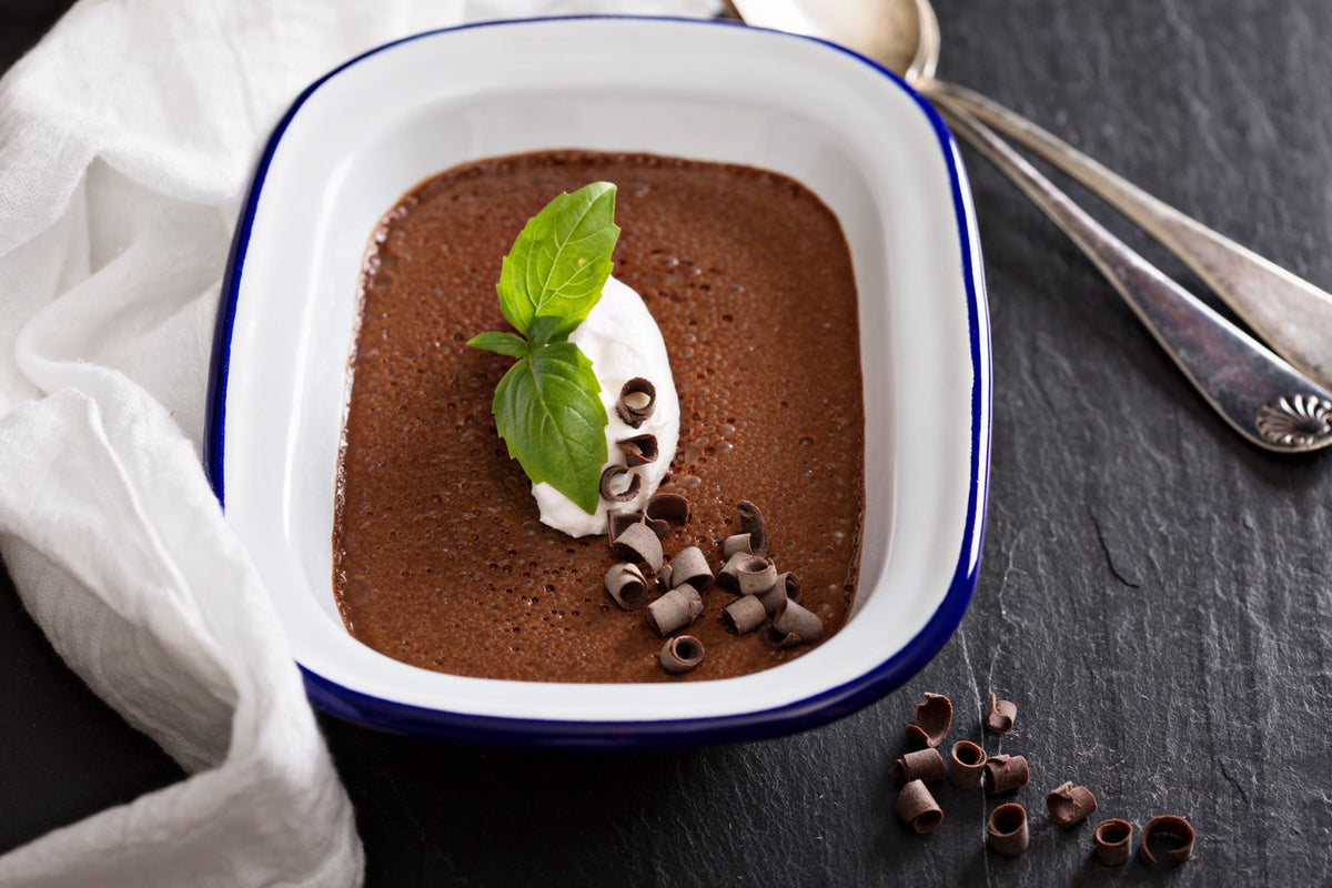 Chocolate dessert topped with cream, fresh green leaves and chocolate curls