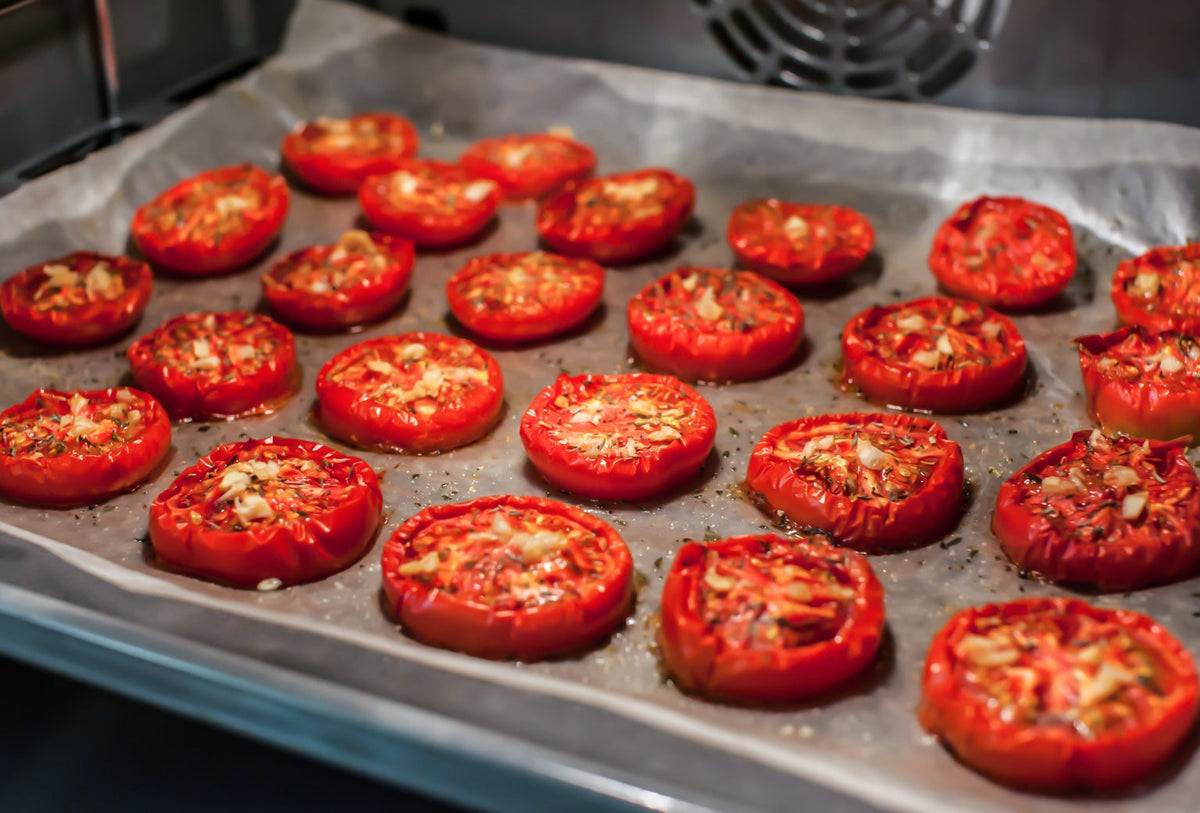 Tomato halves with garlic and herbs roasting on a parchment-lined baking tray