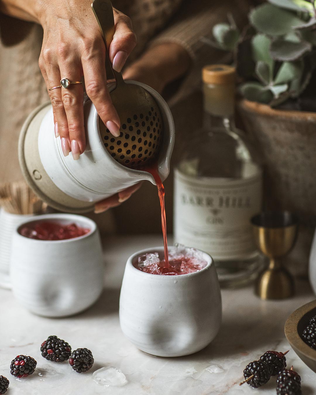 A berry cocktail being poured from the Countryman Cocktail Beaker into a pottery cup