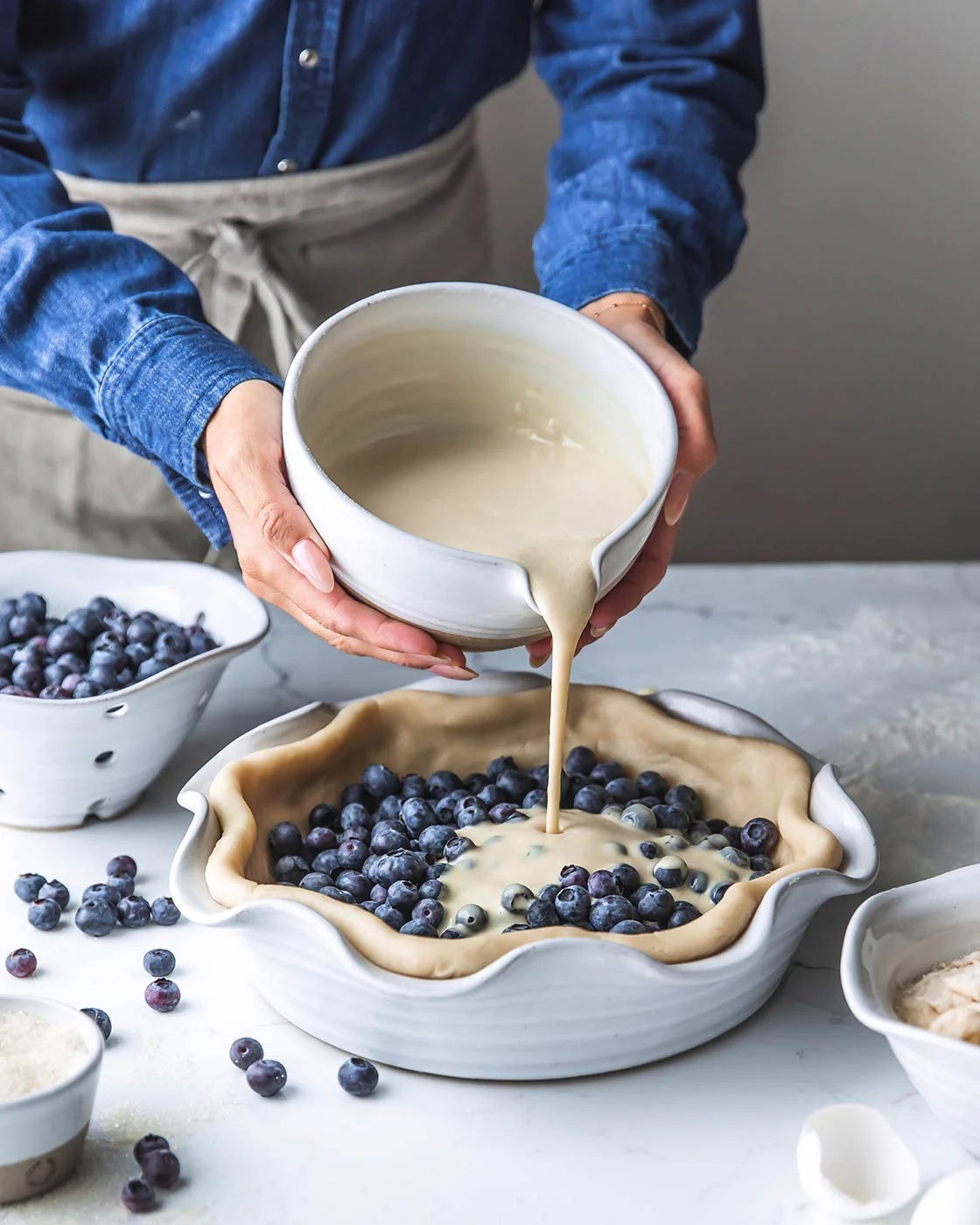 Pouring batter from Pantry Bowl over blueberries