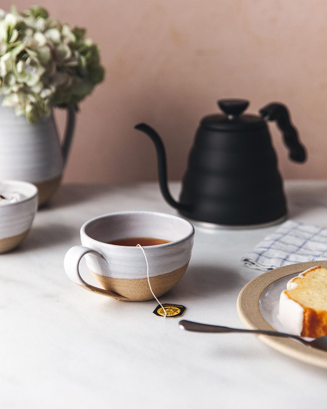 Farmhouse Pottery Pantry Mug with tea beside a black kettle and cake