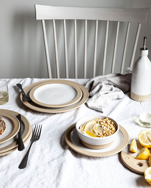 Silo Bowl filled with hummus on a white linen dining table with stoneware plates