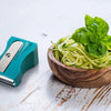 Teal Karoto Julienne beside a wooden bowl of thin zucchini strips topped with basil