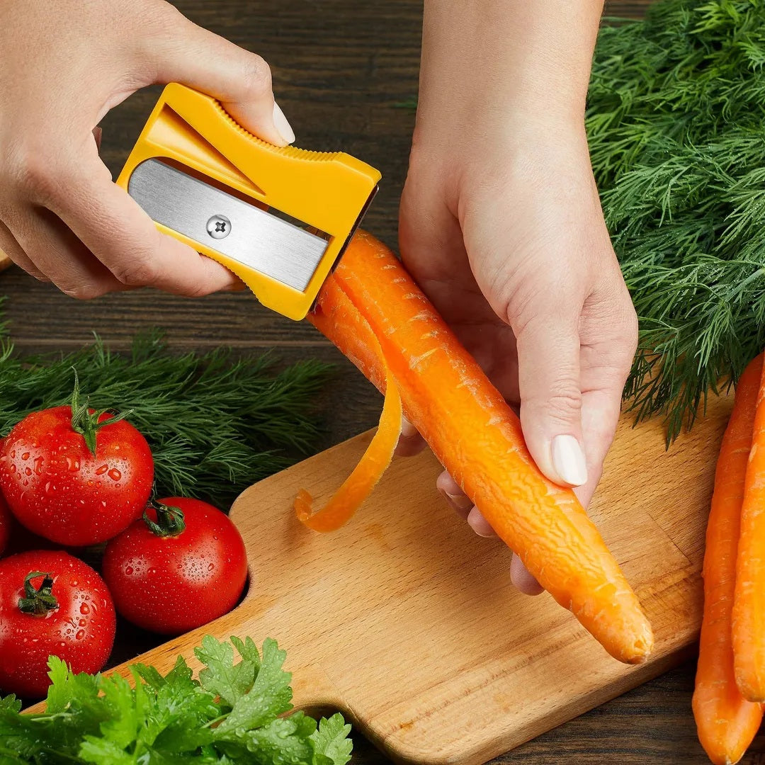 Using the straight peeling blade of a yellow Karoto to peel a carrot over a wooden cutting board